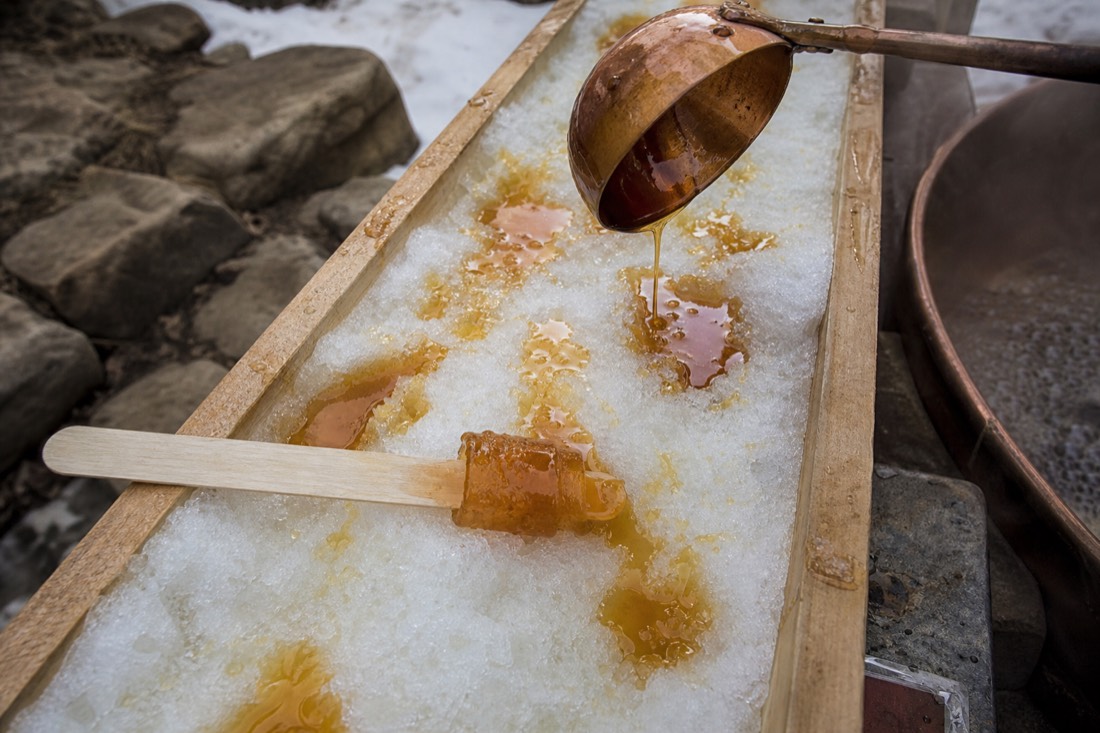Hot maple syrup poured onto packed snow and rolled onto a stick at a Quebec sugar shack