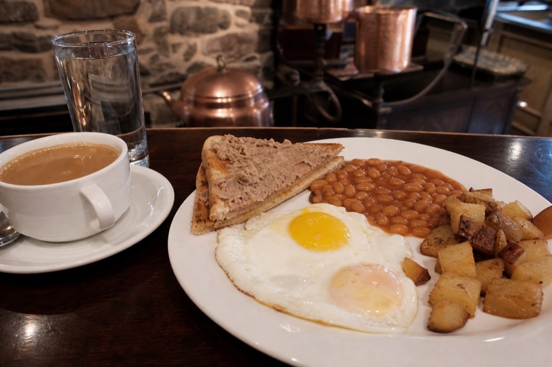 Toast spread with cretons beside eggs and baked beans at a Quebec City breakfast counter