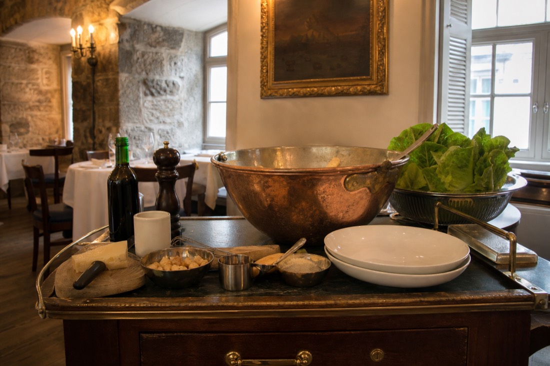 Tableside Caesar salad being prepared on a service trolley in a classic Quebec City dining room