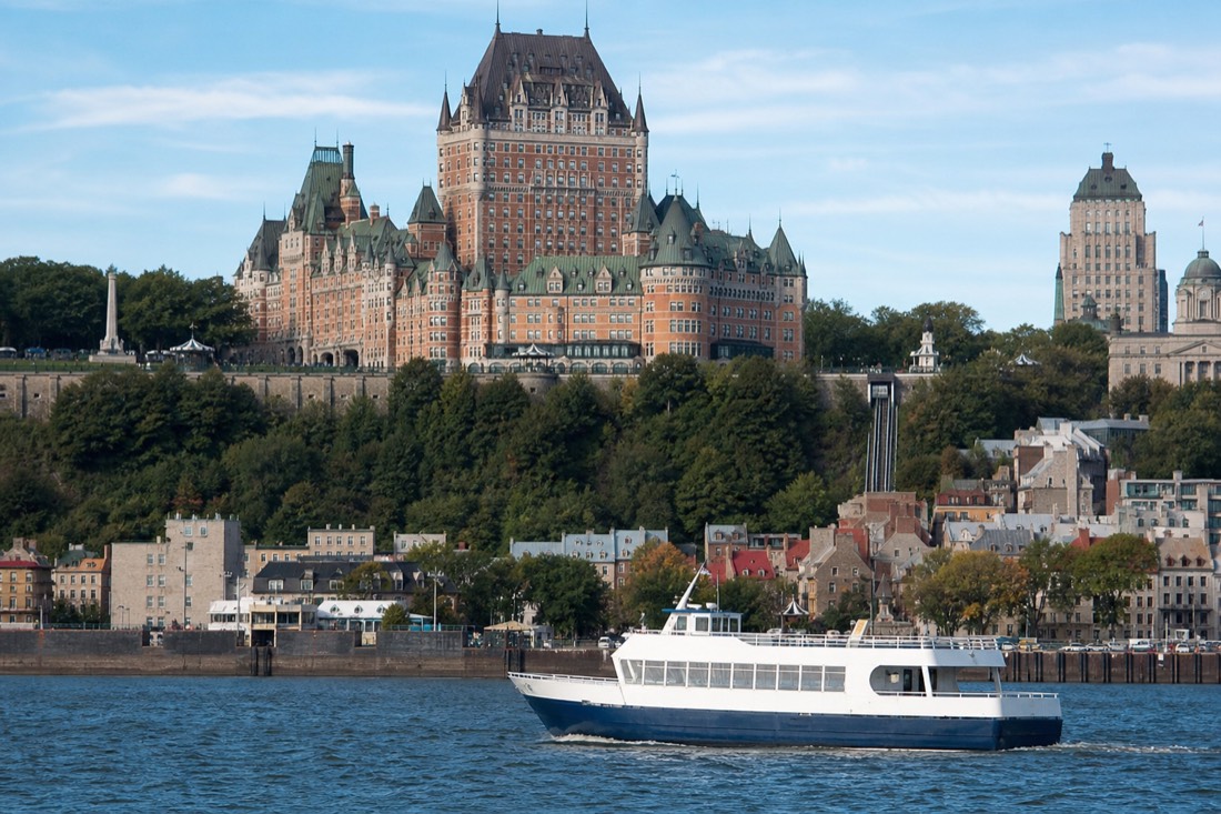 Sightseeing cruise boat on the St. Lawrence River with the cliff and Château Frontenac of Quebec City behind