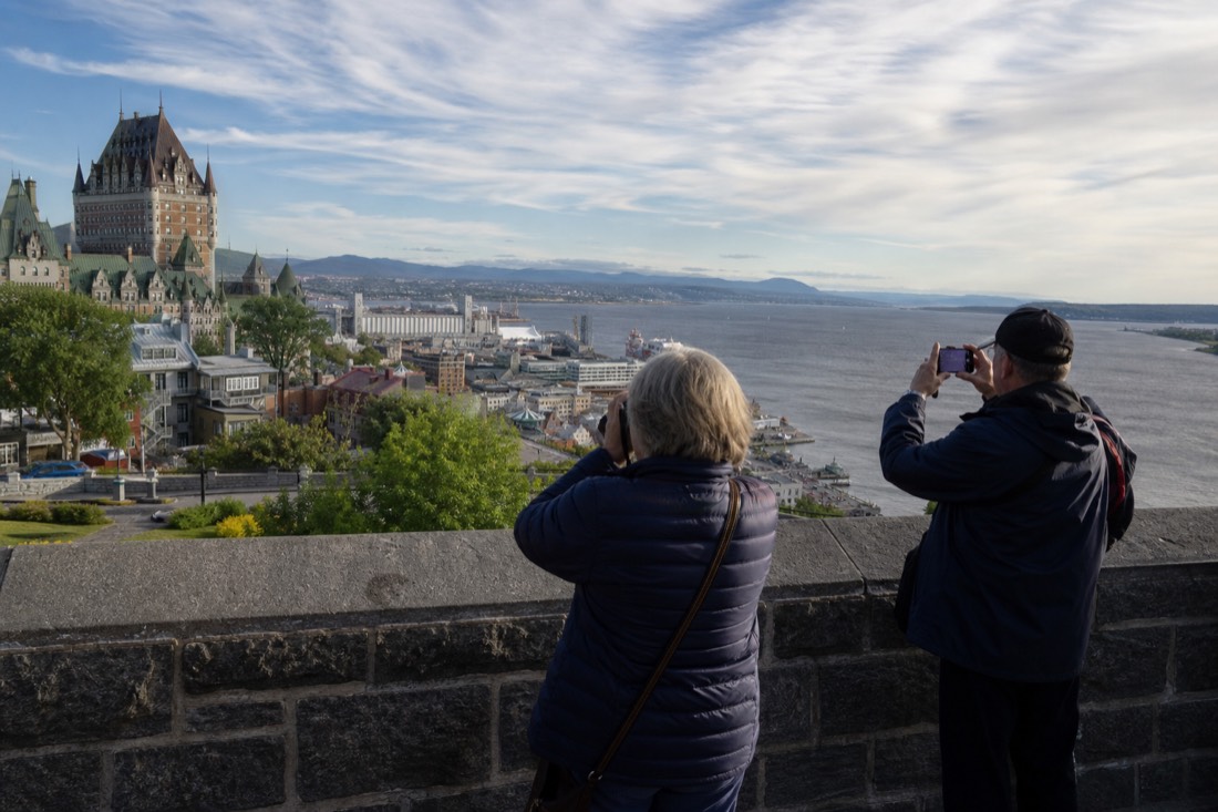 Visitors photographing the Old Quebec skyline from a riverside viewpoint on the St. Lawrence