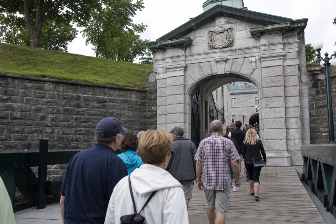 Visitors following a guide through the stone entrance gate of the Citadelle of Quebec on a guided tour