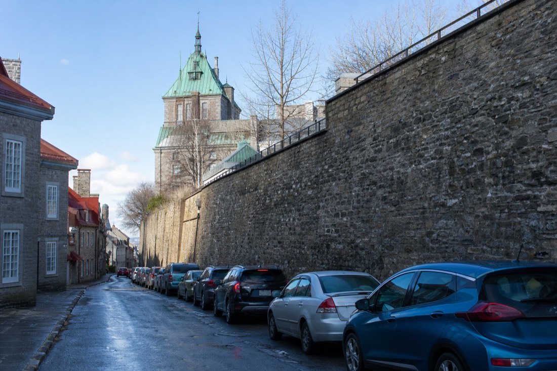 Cars parked along a narrow one-way street below stone ramparts in Old Quebec