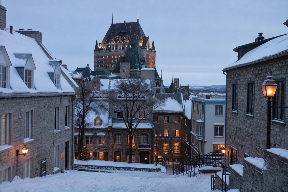 Snow-covered Old Quebec street with lit windows in winter, the base for a day trip to the ice hotel