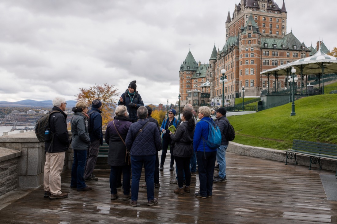 Walking tour group listening to a guide on Dufferin Terrace beside the Chateau Frontenac in Quebec City