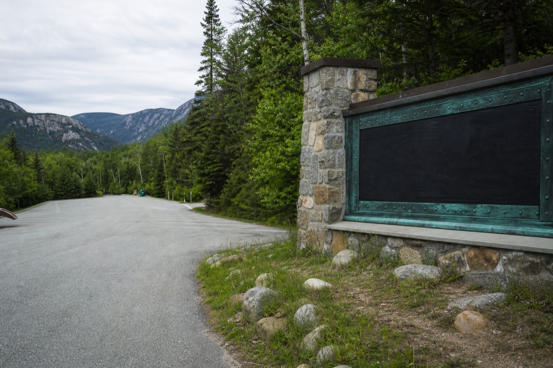 Empty parking area and trailhead sign at the entrance to Parc national de la Jacques-Cartier