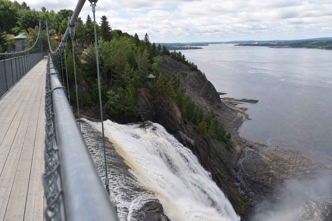 Visitors on the suspension bridge above Montmorency Falls looking down the 83-metre drop toward the St. Lawrence