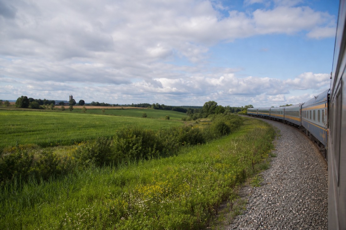 VIA Rail train on the Montreal to Quebec City corridor passing farmland on a summer afternoon