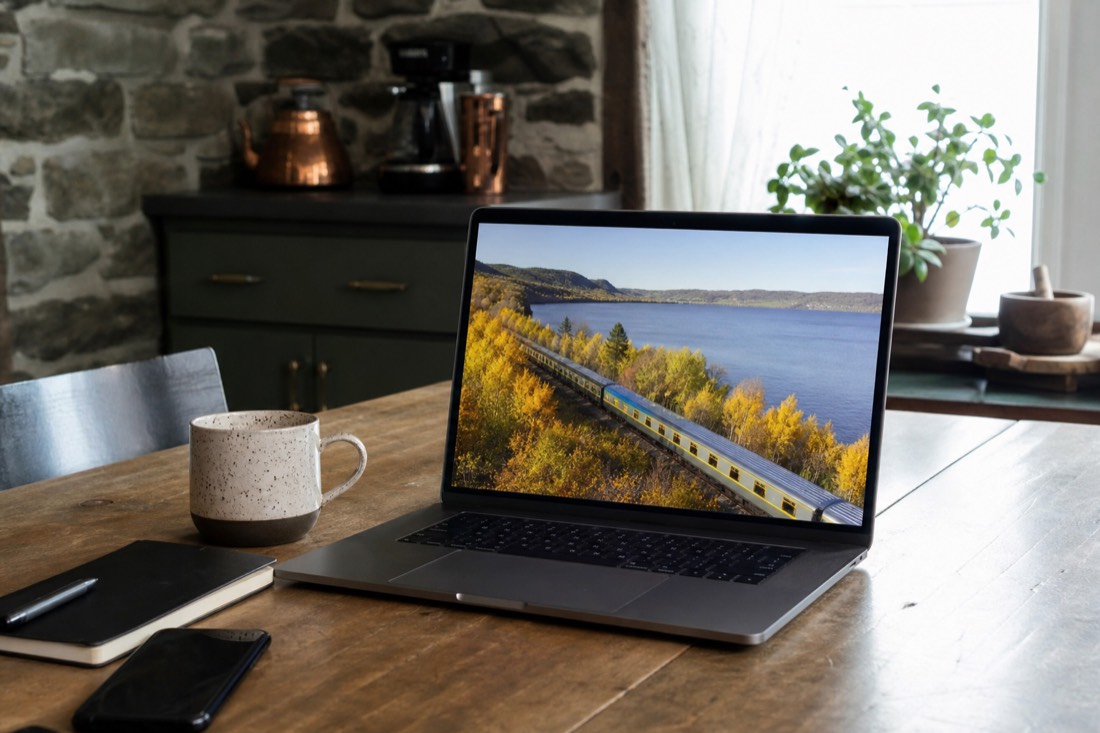 Traveller booking a VIA Rail ticket to Quebec City on a laptop at a kitchen table