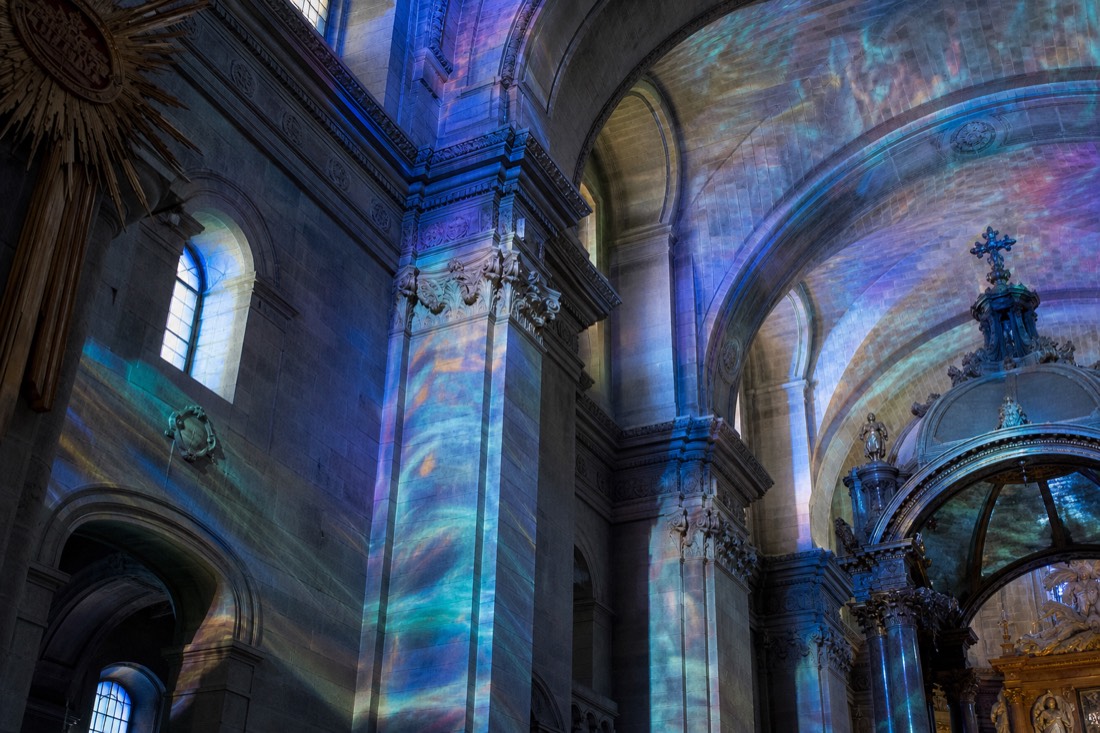 Coloured light projected across the vaulted stone interior of a Quebec church during an immersive AURA style show