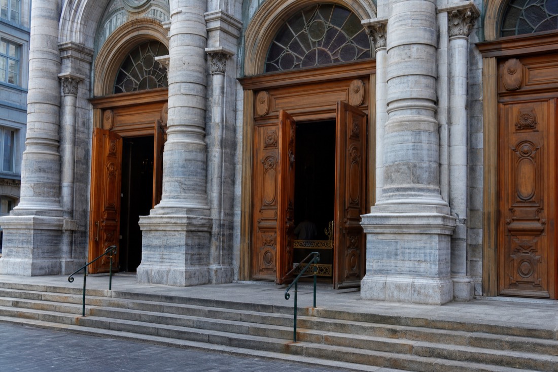 Visitors entering the wooden doors of the Notre-Dame de Québec Basilica-Cathedral during daytime opening hours