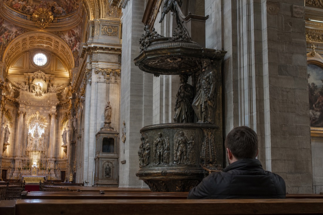 Traveller sitting quietly in a pew inside a historic Quebec City basilica taking time over the visit