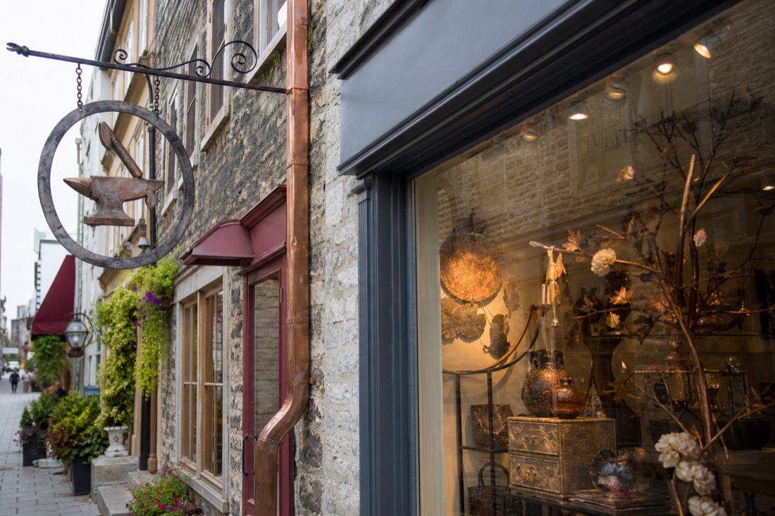 Artisan boutique window and hanging iron sign on rue du Petit-Champlain, one of more than 40 shops on the street