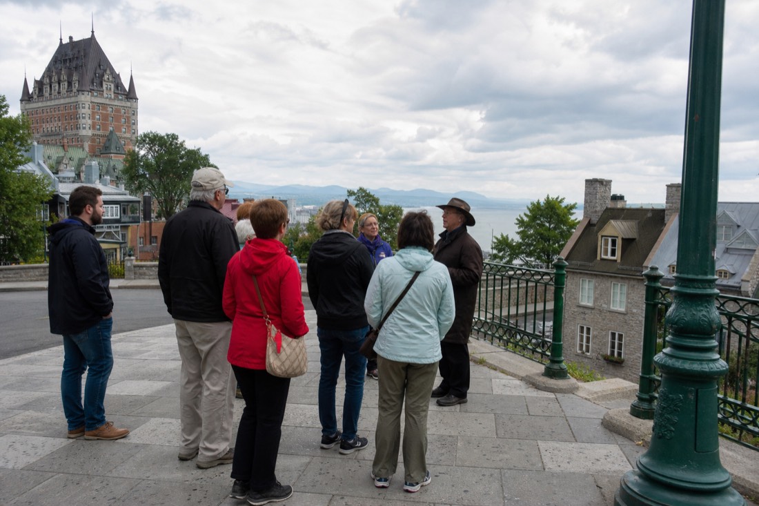 Small guided walking tour group listening to a guide at the top of rue du Petit-Champlain in Quebec City