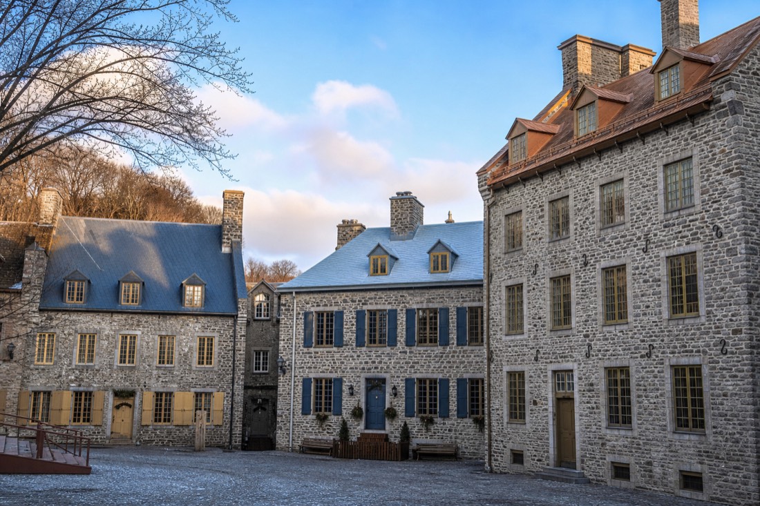 Restored 17th and 18th-century stone houses with steep roofs and dormers surrounding Place Royale in Quebec City