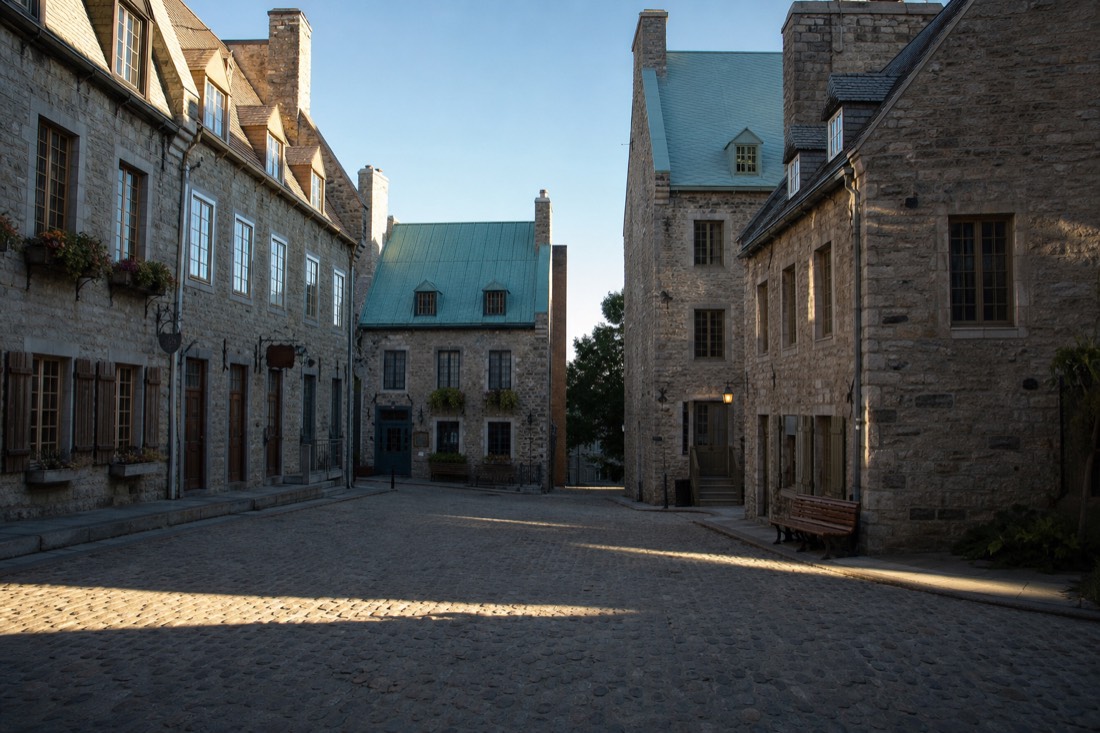 Early morning light on the empty cobblestones of Place Royale with long shadows between the stone facades