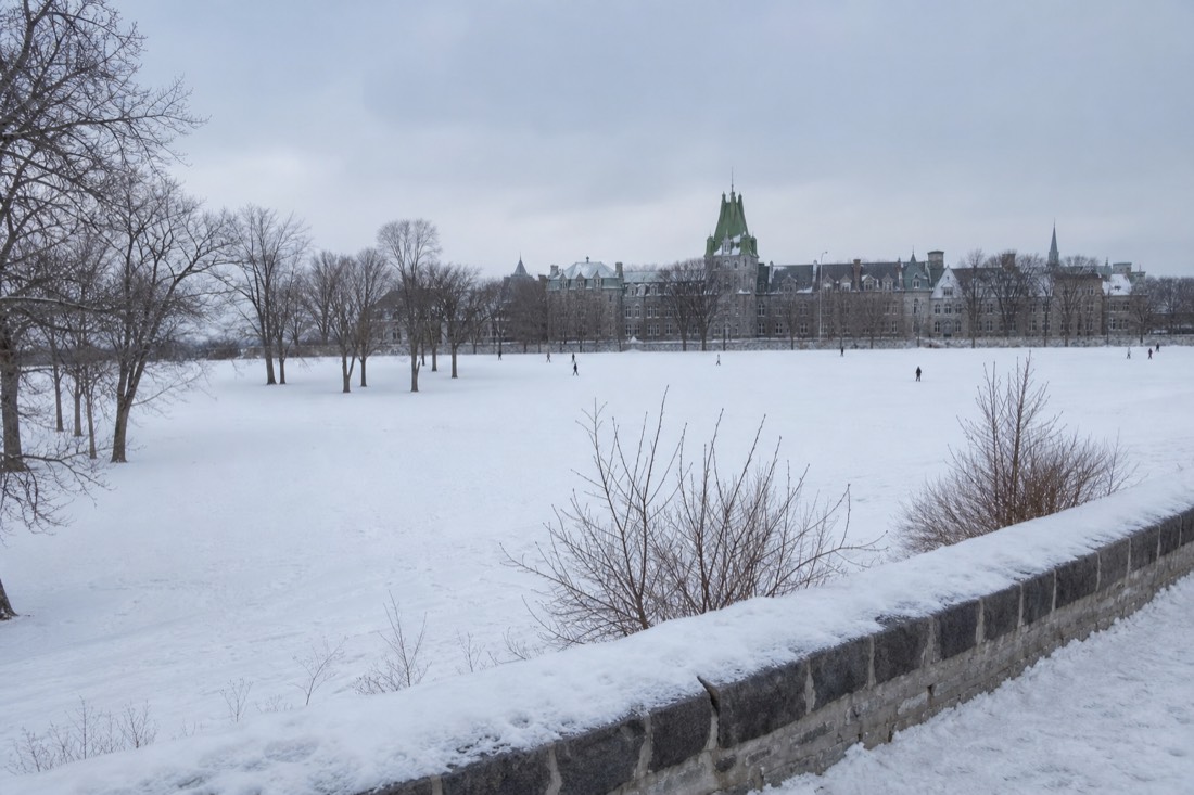 Snow-covered Plains of Abraham in winter with bare trees and walkers crossing the open field