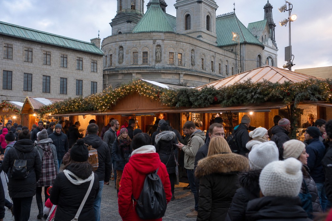 Crowd of visitors around food kiosks at the Quebec City German Christmas Market on a busy December evening