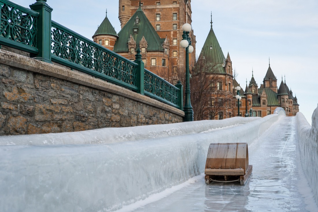 Wooden toboggan speeding down the icy slide on Dufferin Terrace beside the Château Frontenac