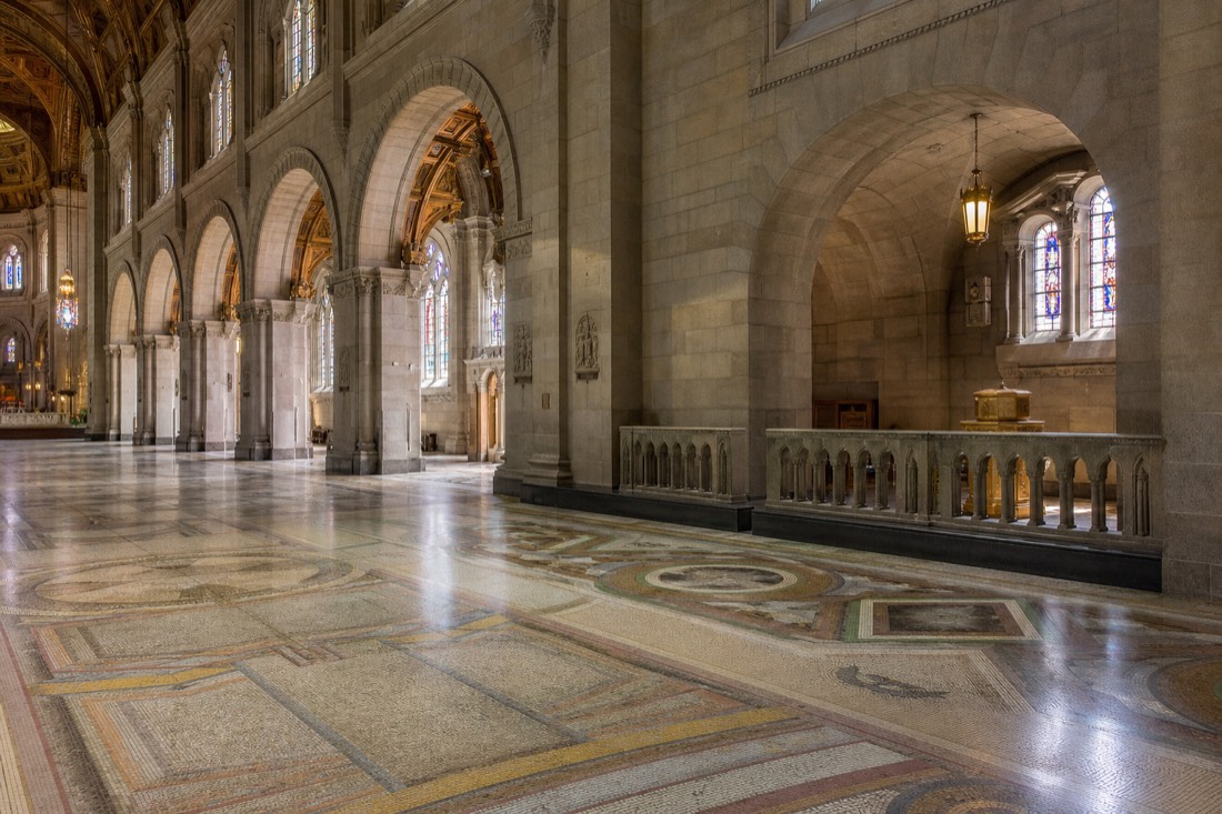 Interior nave of the Sainte-Anne-de-Beaupre basilica showing mosaic floor, columns and stained glass windows